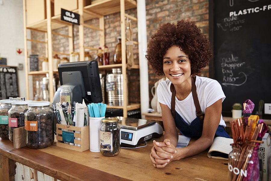Business Insurance - Closeup View of Happy Young Business Owner Standing Behind the Counter in Her Coffee Shop